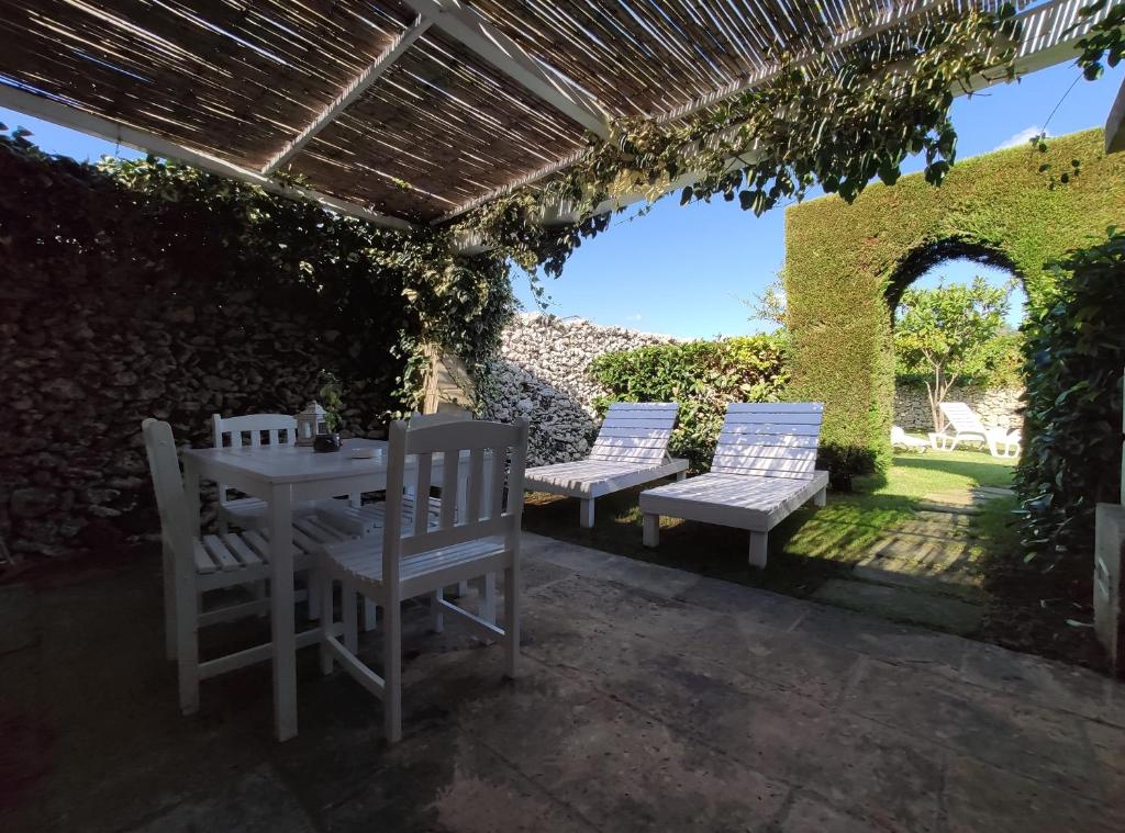 un patio avec trois chaises et une table et une table et des bancs dans l'établissement Masseria Salentina Costarella, à Borgagne