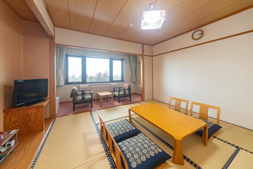 - un salon avec une table en bois et une télévision dans l'établissement Kyukamura Myoko, à Myōkō