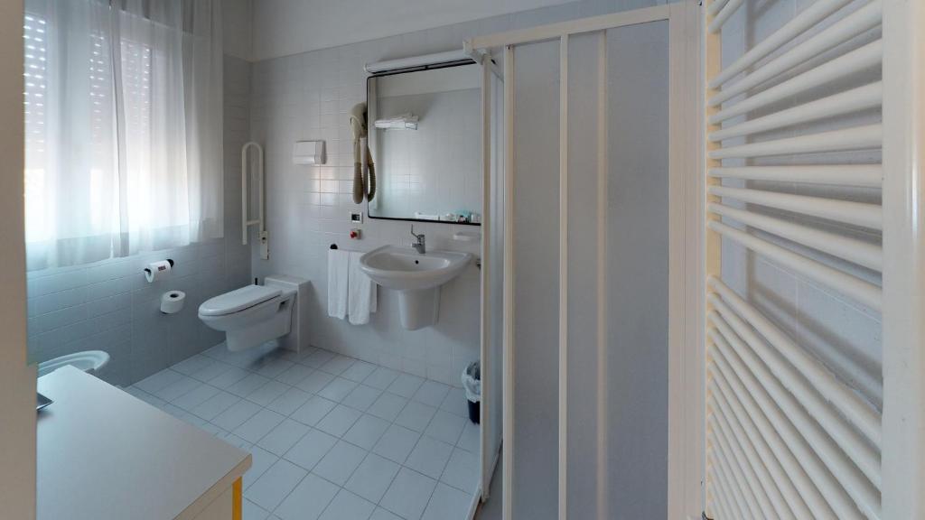 une salle de bain blanche avec toilettes et lavabo dans l'établissement Hotel Villa Sorriso, à Lido di Jesolo