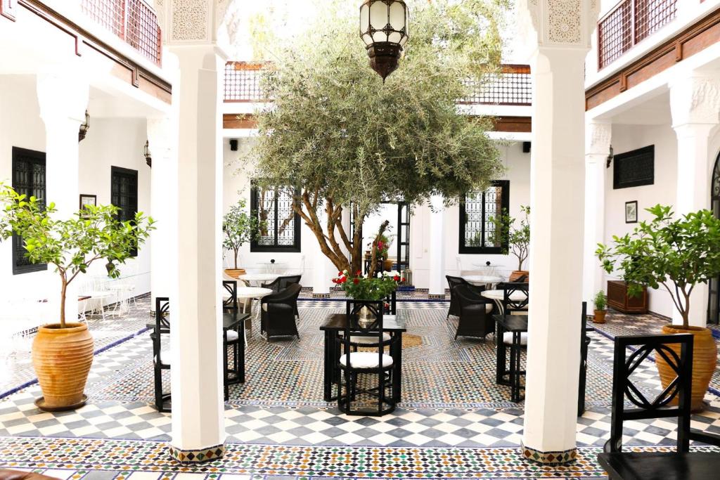 une cour avec des tables et des chaises dans un bâtiment dans l'établissement Riad Bellamane Marrakech, à Marrakech