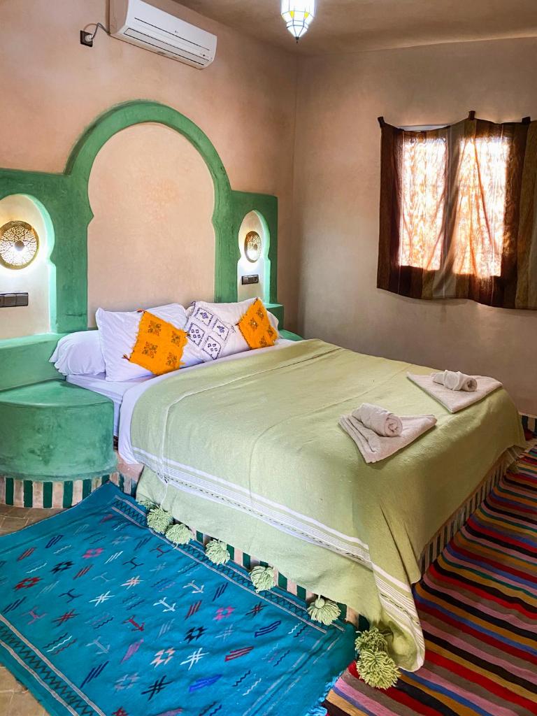une chambre avec un grand lit avec une tête de lit verte dans l'établissement Maison Hassan Merzouga, à Merzouga
