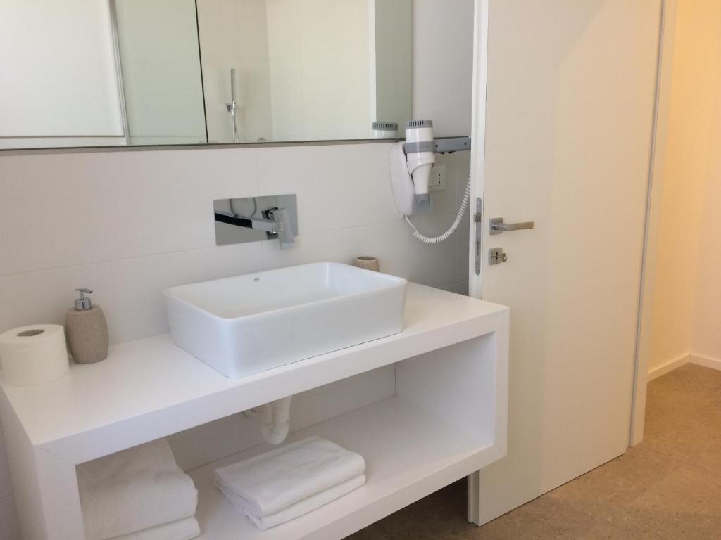 une salle de bain blanche avec un lavabo et un miroir dans l'établissement Milan Residence, à Rosolina Mare 26 autres photos