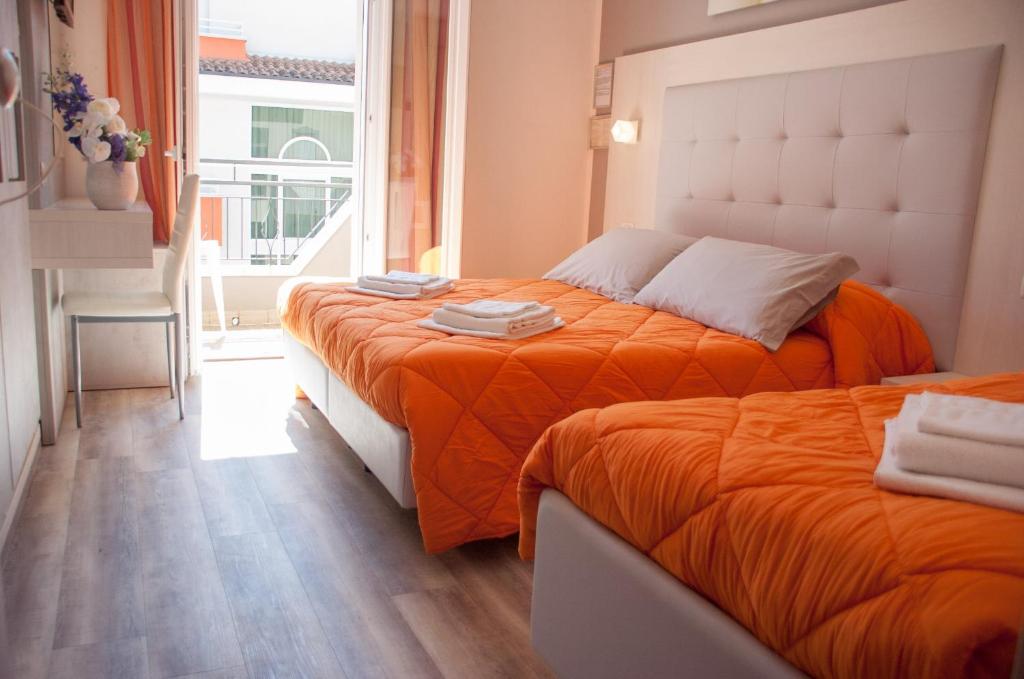 - 2 lits avec des draps orange dans une chambre avec une fenêtre dans l'établissement Albergo Villa Miraggio, à Rimini