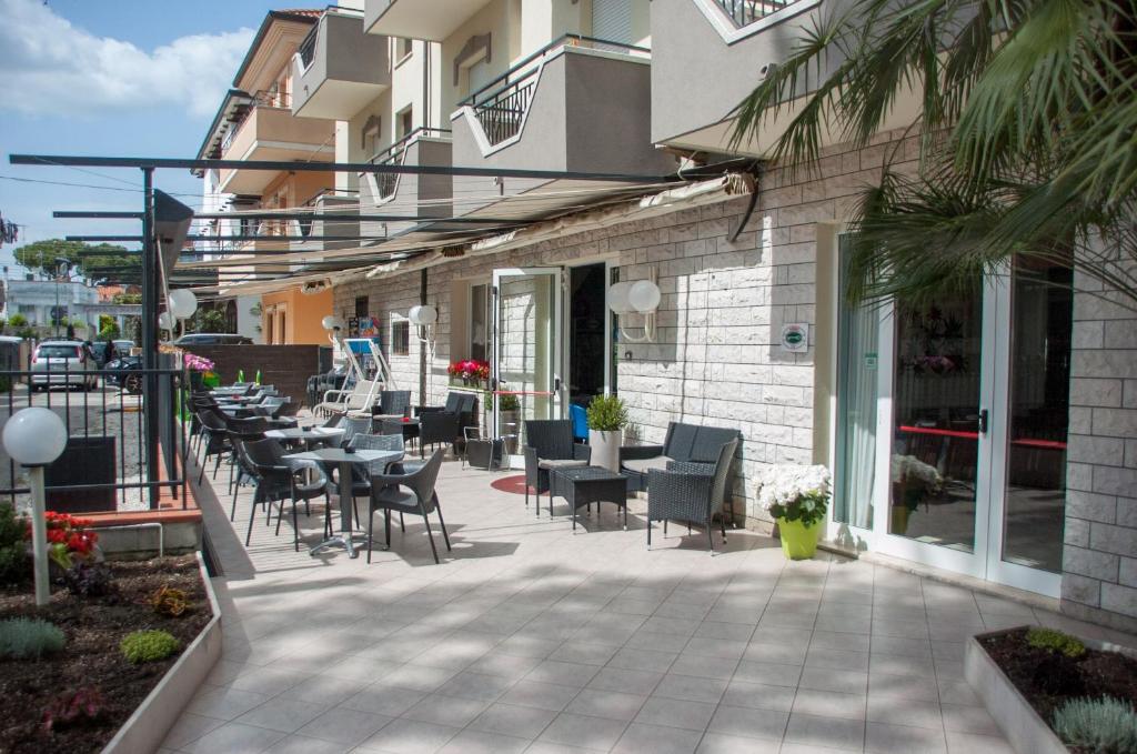 un patio avec des tables et des chaises à côté d'un bâtiment dans l'établissement Albergo Villa Miraggio, à Rimini