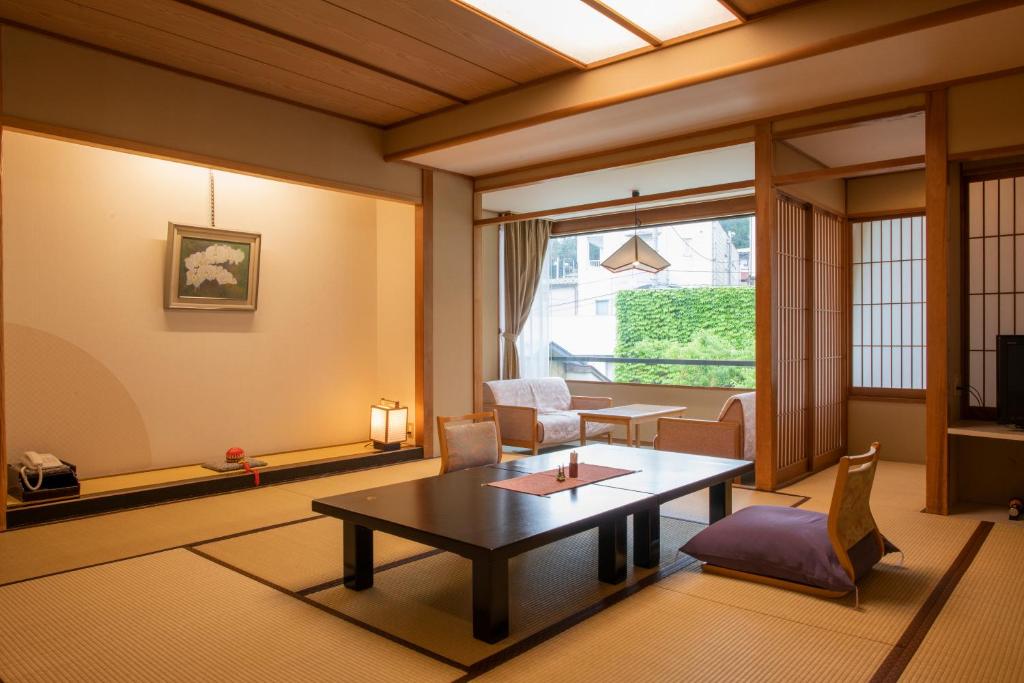 un salon avec une table et des chaises et une fenêtre dans l'établissement Shosenkaku Kagetsu, à Yuzawa