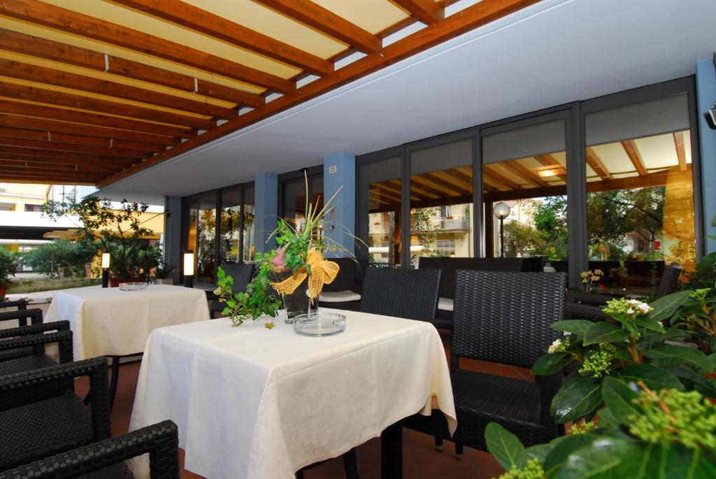 une salle à manger avec deux tables et chaises et des fenêtres dans l'établissement Hotel Ambasciata, à Cesenatico
