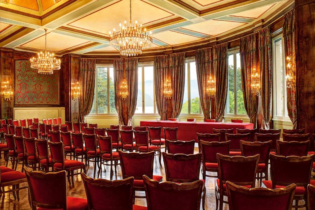une salle de conférence avec des chaises rouges et des lustres dans l'établissement Grand Hotel Majestic, à Verbania 90 autres photos
