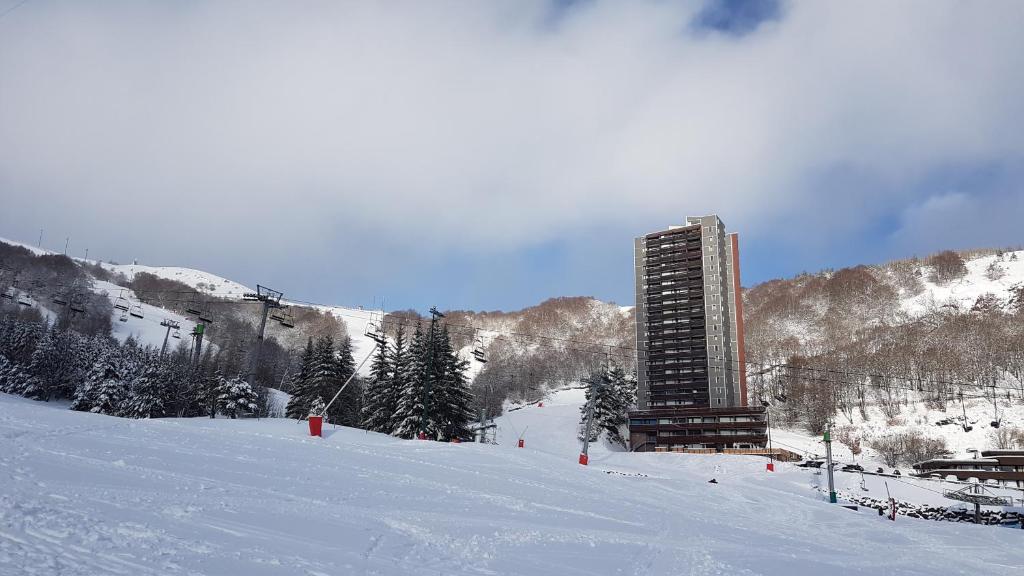 un bâtiment au sommet d'une piste de ski enneigée dans l'établissement Studio-cabine au pied des pistes à Super Besse, à Super-Besse
