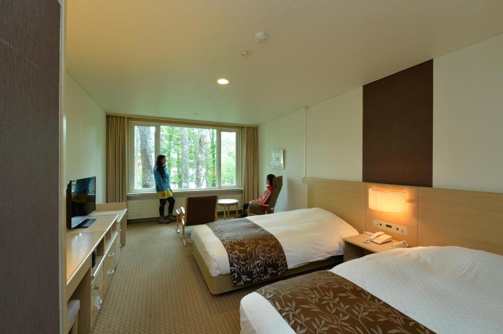 une chambre d'hôtel avec deux lits et une fenêtre dans l'établissement Kyukamura Nikko-Yumoto, à Nikkō