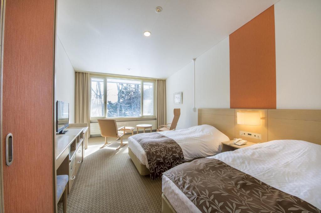 une chambre d'hôtel avec deux lits et un bureau dans l'établissement Kyukamura Nikko-Yumoto, à Nikkō