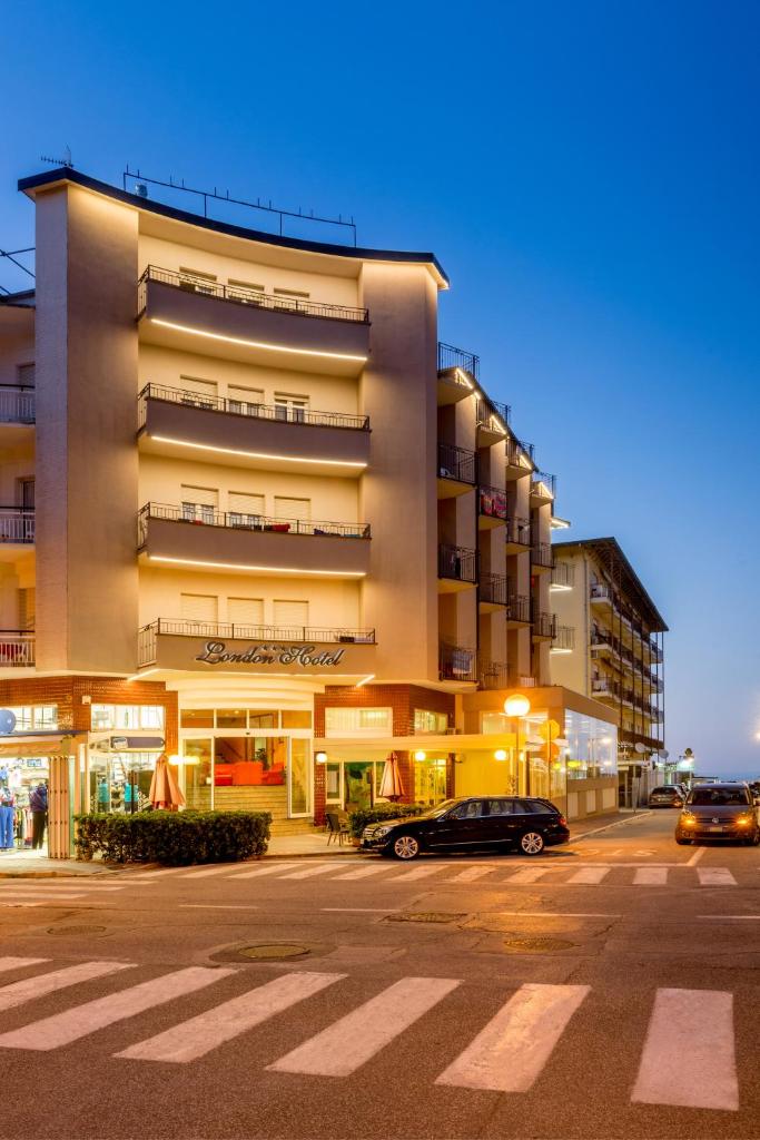 un bâtiment avec des voitures garées dans un parking dans l'établissement Hotel London, à Cattolica