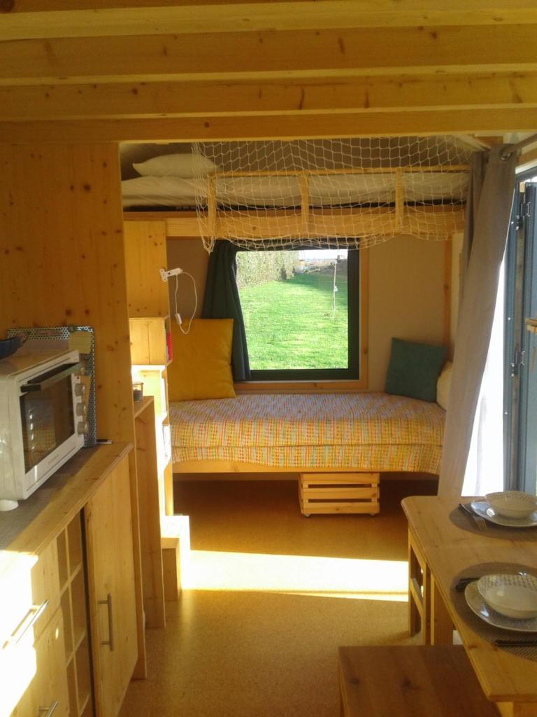 une petite chambre avec un canapé dans une petite maison dans l'établissement Tiny house sur la Presqu'île Sauvage, à Lanmodez