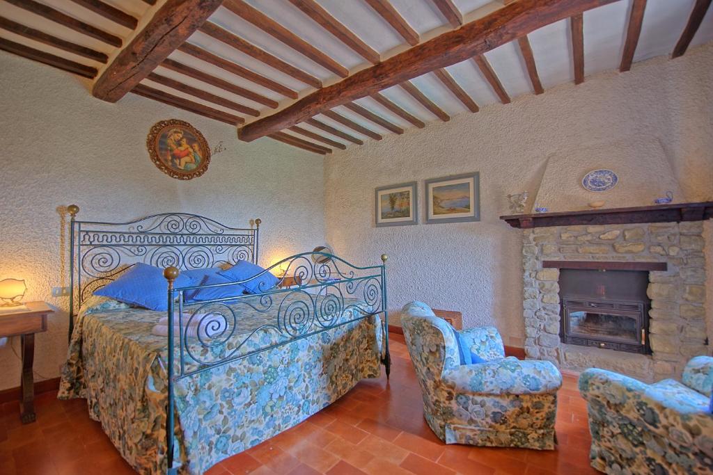 une chambre avec un lit et deux chaises et une cheminée dans l'établissement Villa Uccellaia by PosarelliVillas, à Agello 38 autres photos