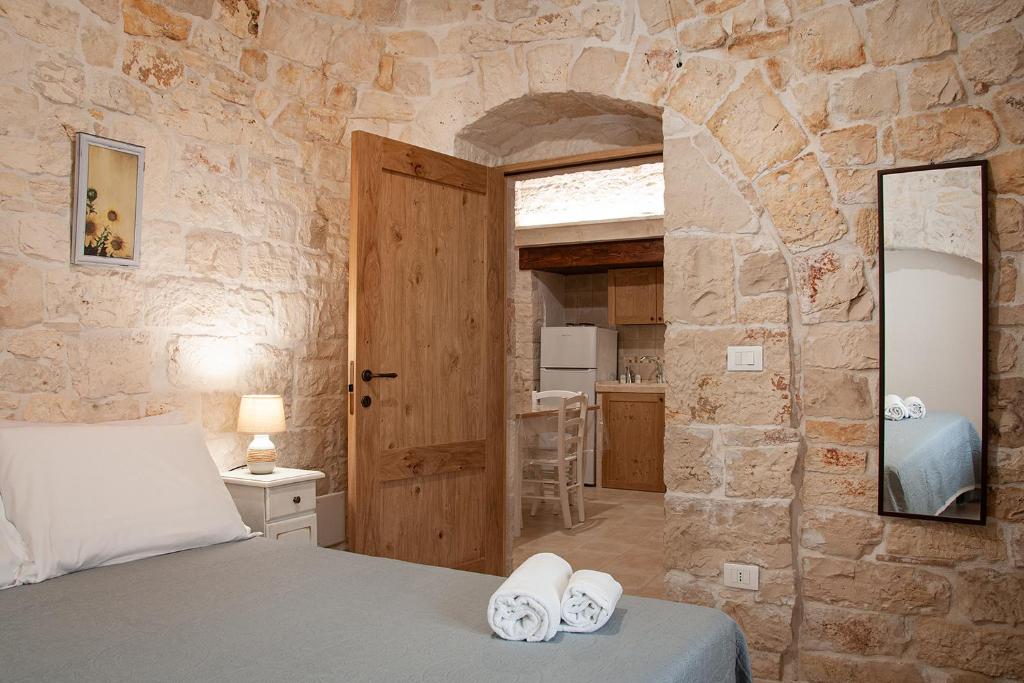 une chambre avec un lit et un mur en pierre dans l'établissement Trulli Loco, à Locorotondo