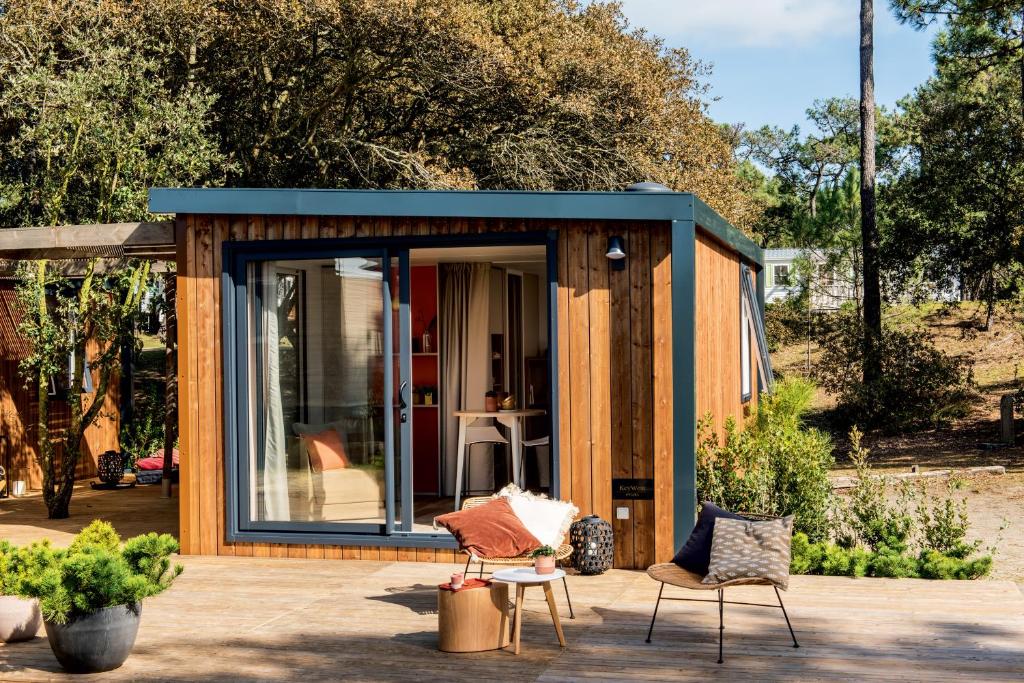 une petite maison avec un toit bleu sur une terrasse dans l'établissement Domaine Les Mûriers, à Vendres-Plage
