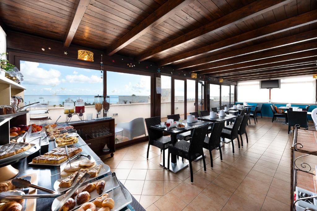 un restaurant avec tables et chaises avec vue sur l'océan dans l'établissement Hotel Baia Di Venere, à San Vito Lo Capo