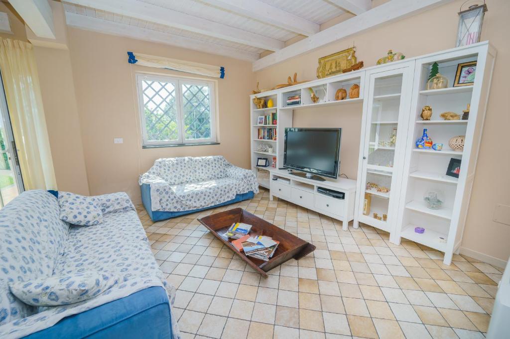 un salon avec un canapé et une télévision dans l'établissement villa dei limoni Etna-mare, à Acireale
