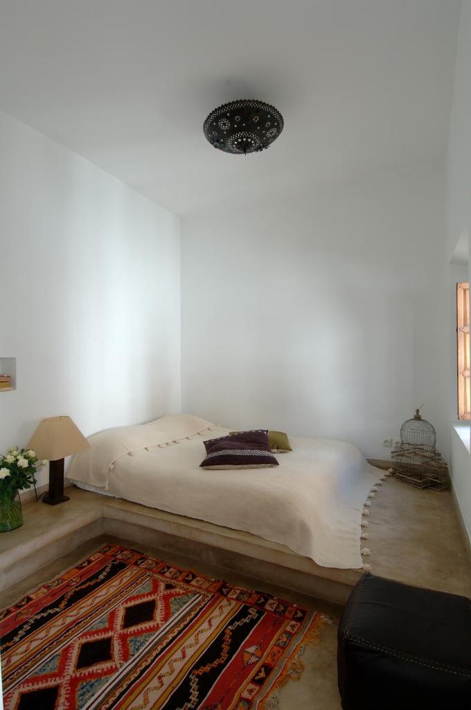 - une chambre blanche avec un lit et un tapis dans l'établissement Riad UP, à Marrakech