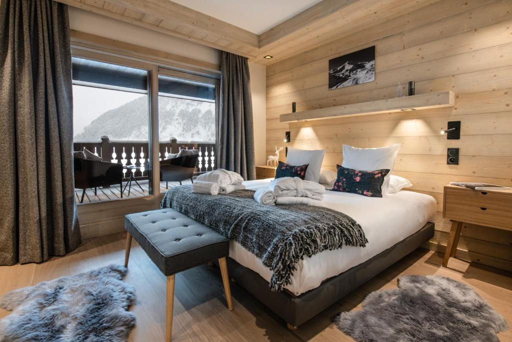 une chambre avec un grand lit et un balcon dans l'établissement Manali Lodge by Alpine Resorts, à Courchevel