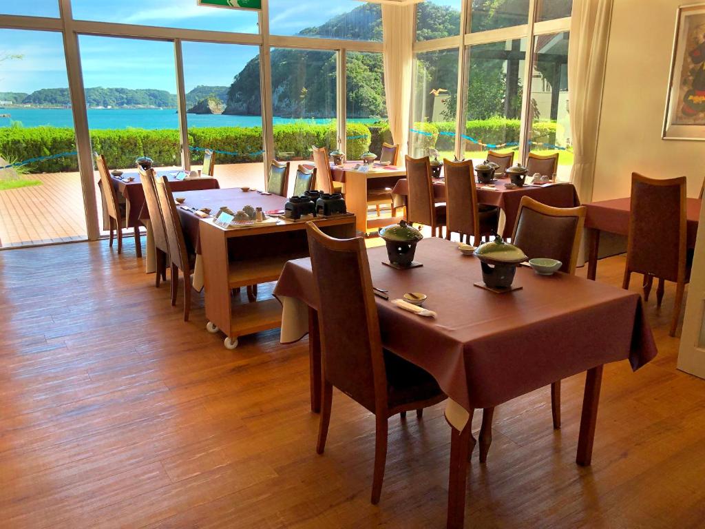 un restaurant avec des tables et des chaises et une grande fenêtre dans l'établissement Hotel Nagisaya, à Katsuura
