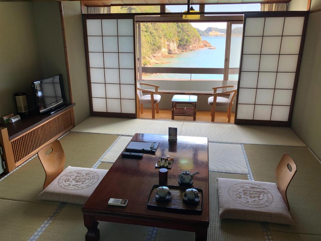 Cette chambre comprend une table et des chaises et offre une vue sur l'eau. dans l'établissement Hotel Nagisaya, à Katsuura