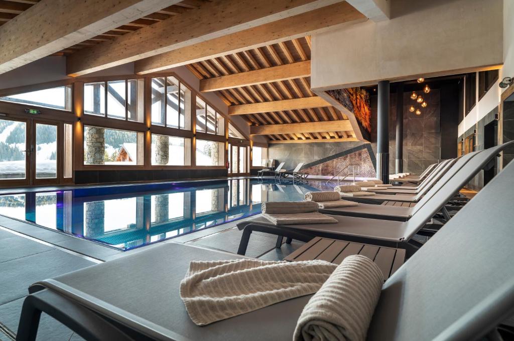 une piscine intérieure avec des chaises et une piscine dans l'établissement MGM Hôtels & Résidences - Résidence Amaya, à Villard-sur-Doron