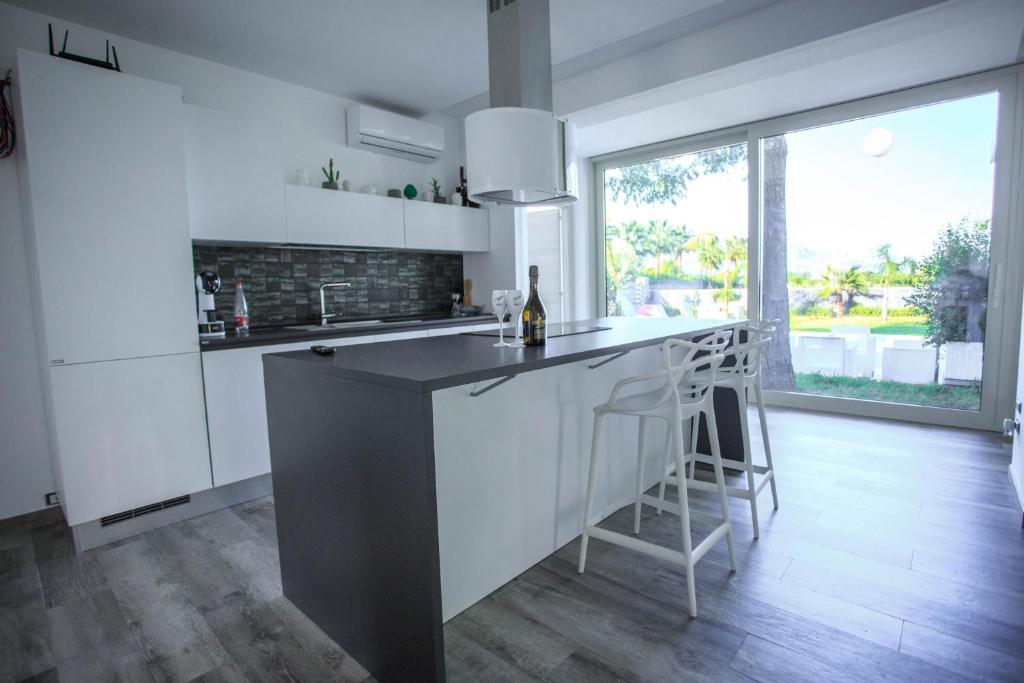 une cuisine avec des placards blancs et un bar avec des tabourets dans l'établissement T Villa, à Calatabiano