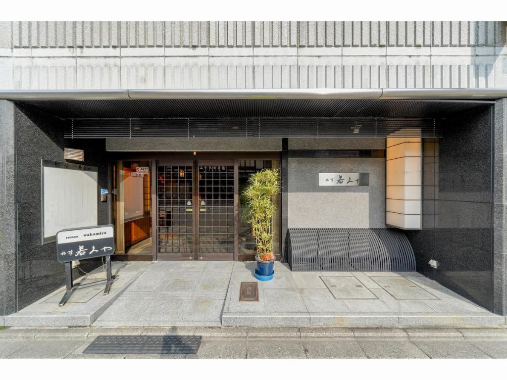 une entrée du bâtiment avec une usine de pot devant elle dans l'établissement Ryokan Wakamiya, à Kyoto