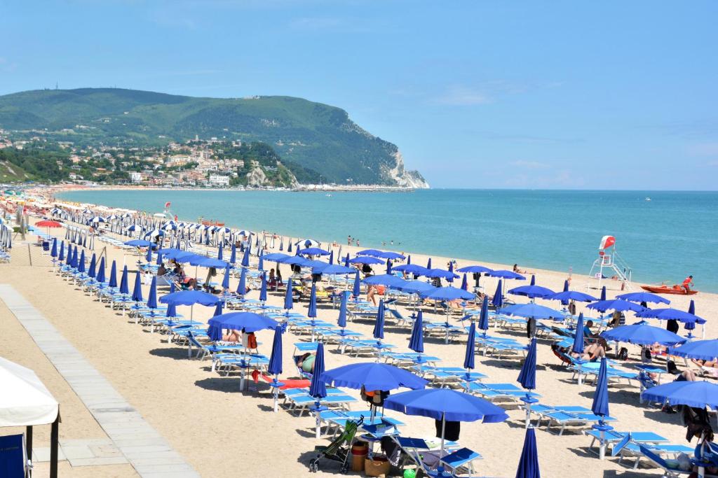 - une plage avec des parasols et des chaises bleus et l'océan dans l'établissement Hotel Galassi, à Numana