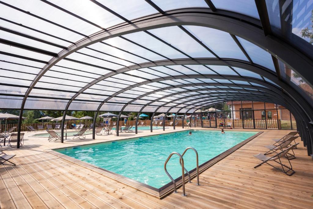une piscine intérieure avec un toit rétractable dans l'établissement Huttopia Lac d'Aiguebelette, à Saint-Alban-de-Montbel