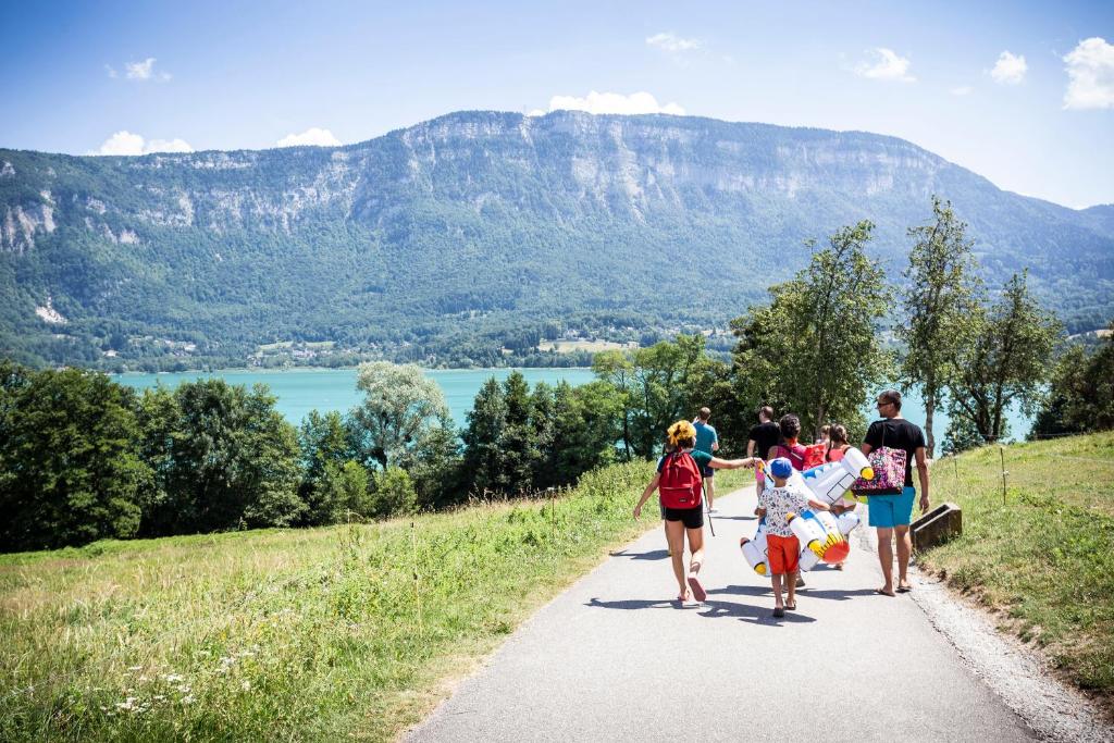 un groupe de personnes se promenant sur un sentier avec des montagnes en arrière-plan dans l'établissement Huttopia Lac d'Aiguebelette, à Saint-Alban-de-Montbel