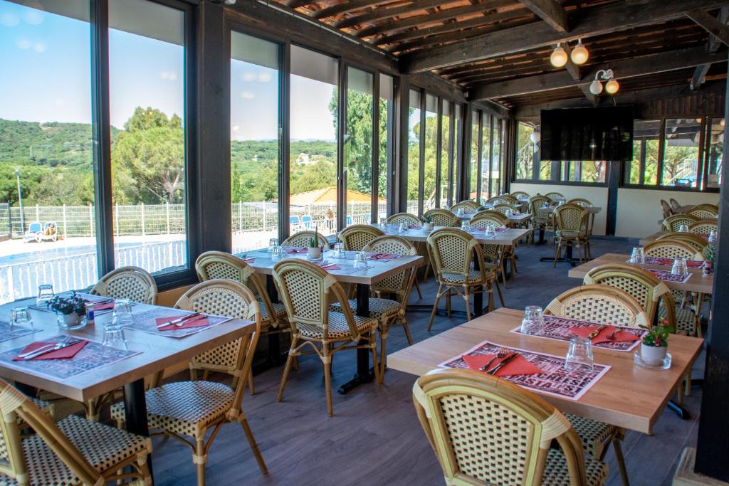 une salle à manger avec tables, chaises et fenêtres dans l'établissement Camping Montana Parc - Gassin Golfe de St Tropez - Maeva, à Gassin