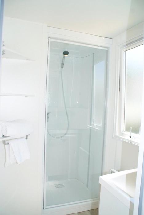 une salle de bain blanche avec une douche avec une porte vitrée dans l'établissement Camping Montana Parc - Gassin Golfe de St Tropez - Maeva, à Gassin
