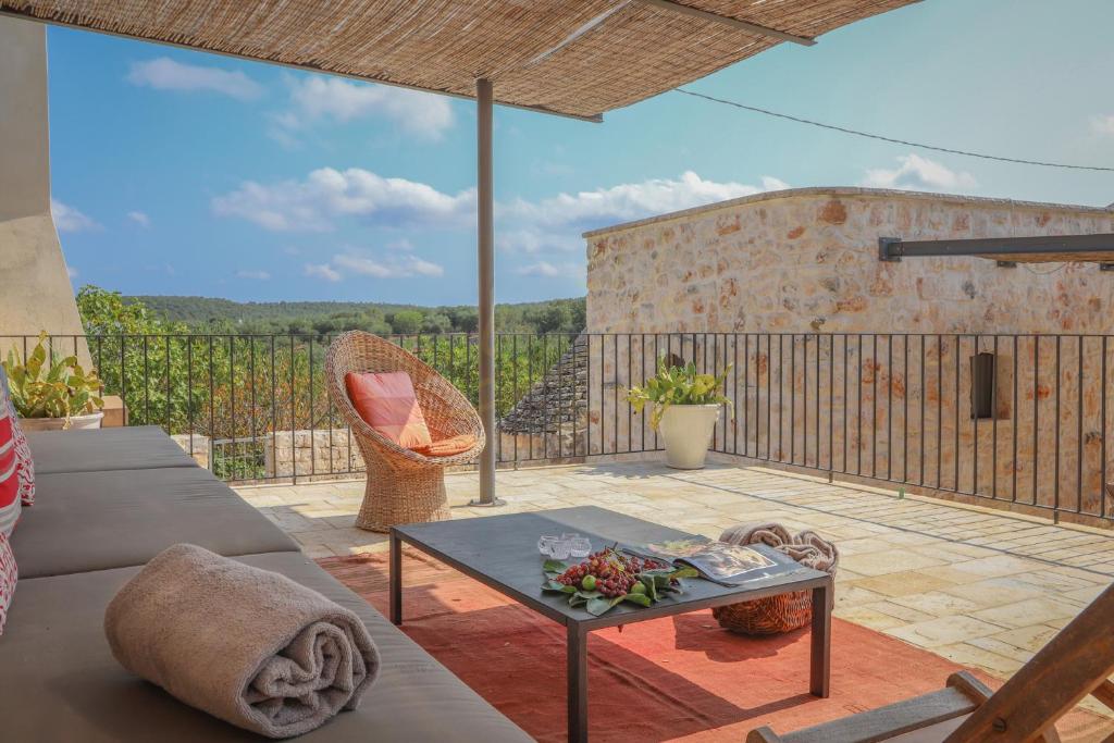 d'une terrasse avec un canapé et une table sur un balcon. dans l'établissement TD Casale Terranova Stone Farmhouse with Pool, à Monopoli