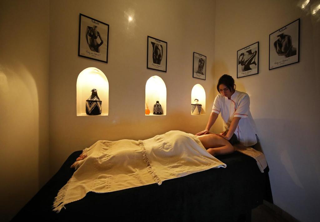 une femme assise au-dessus d'un lit dans l'établissement Riad Anyssates, à Marrakech