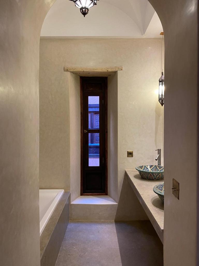 une salle de bain avec une baignoire, un lavabo et une fenêtre dans l'établissement Kasbah Tamsna, à Ouarzazate