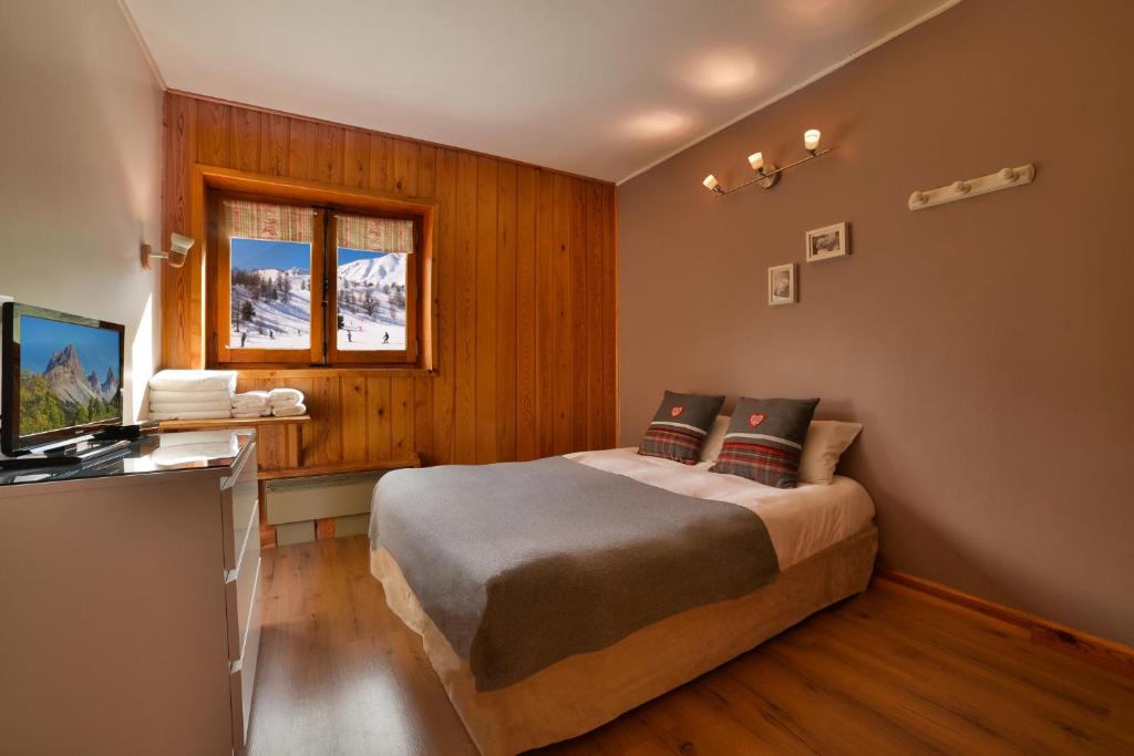 une chambre avec un lit et une télévision dans l'établissement le Chal'heureux, à Vars