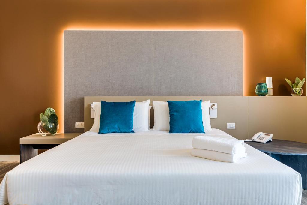 une chambre avec un grand lit blanc avec des oreillers bleus dans l'établissement Seawater Hotel Bio & Beauty Spa, à Marsala 147 autres photos