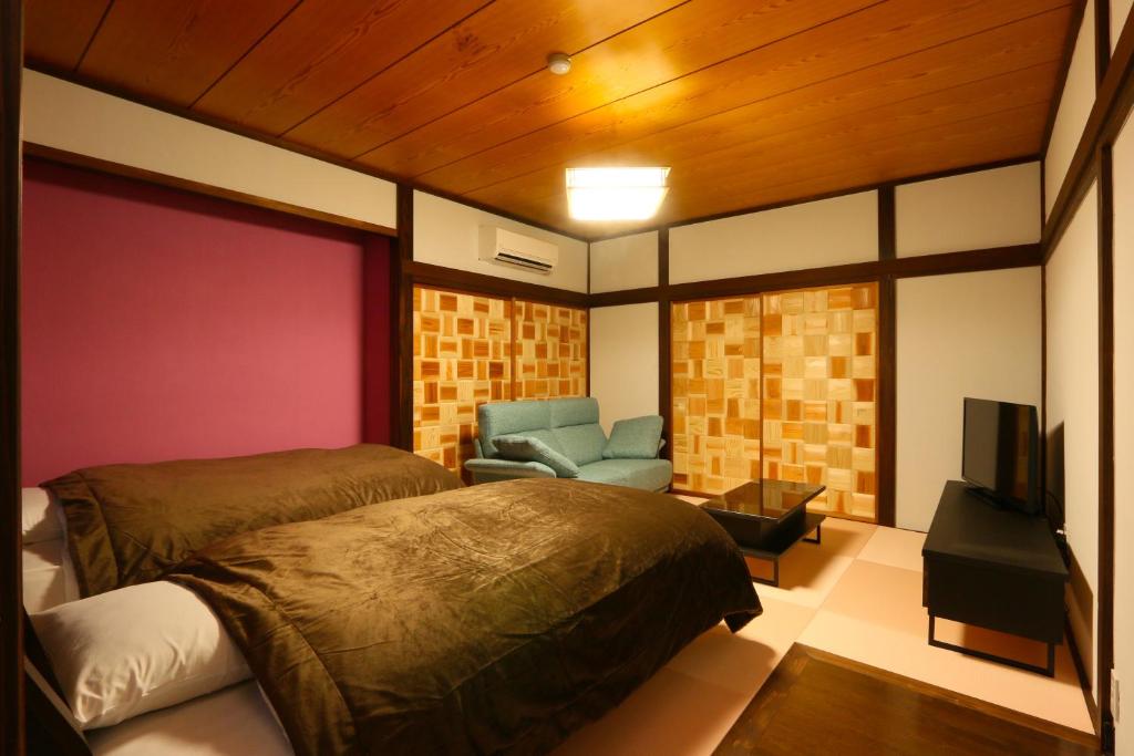 une chambre avec un lit, une chaise et une télévision dans l'établissement Amis Droles アミドローラ LIBERTY RESORT, à Kawazu