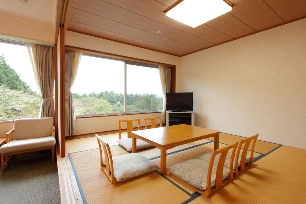 une pièce avec une table, des chaises et une télévision dans l'établissement Kagetsuen, à Hakone