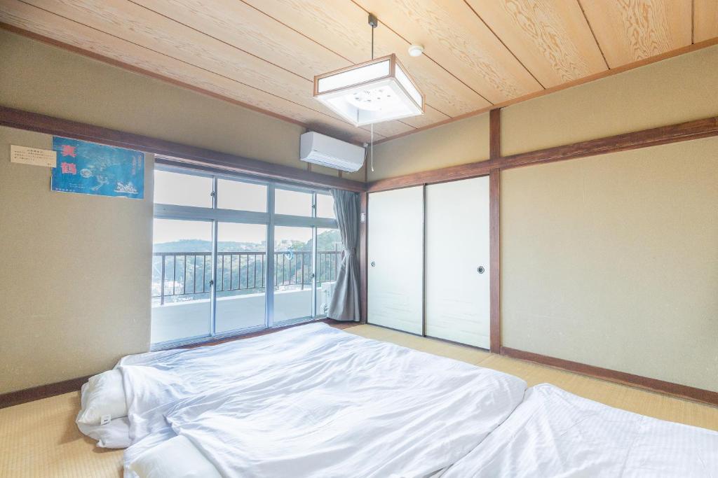 une chambre avec un lit et une grande fenêtre dans l'établissement Tabist Miyoshi Ryokan Odawara Manazuru, à Odawara