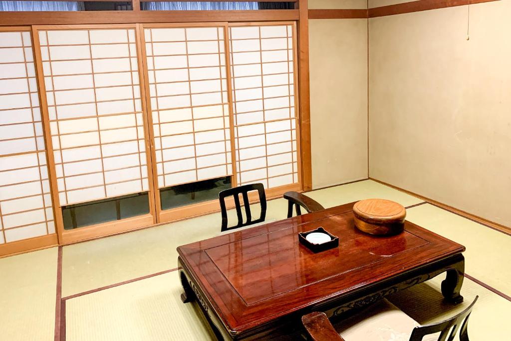 une pièce avec une table, des chaises et des fenêtres dans l'établissement Tabist Kappo-Ryokan Ooriya Kochi, à Sagamichō
