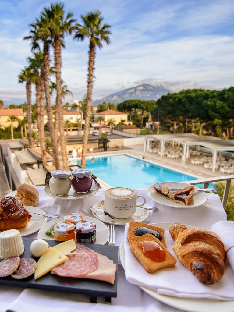 - une table avec des assiettes de nourriture à côté de la piscine dans l'établissement Hotel Cerere, à Paestum