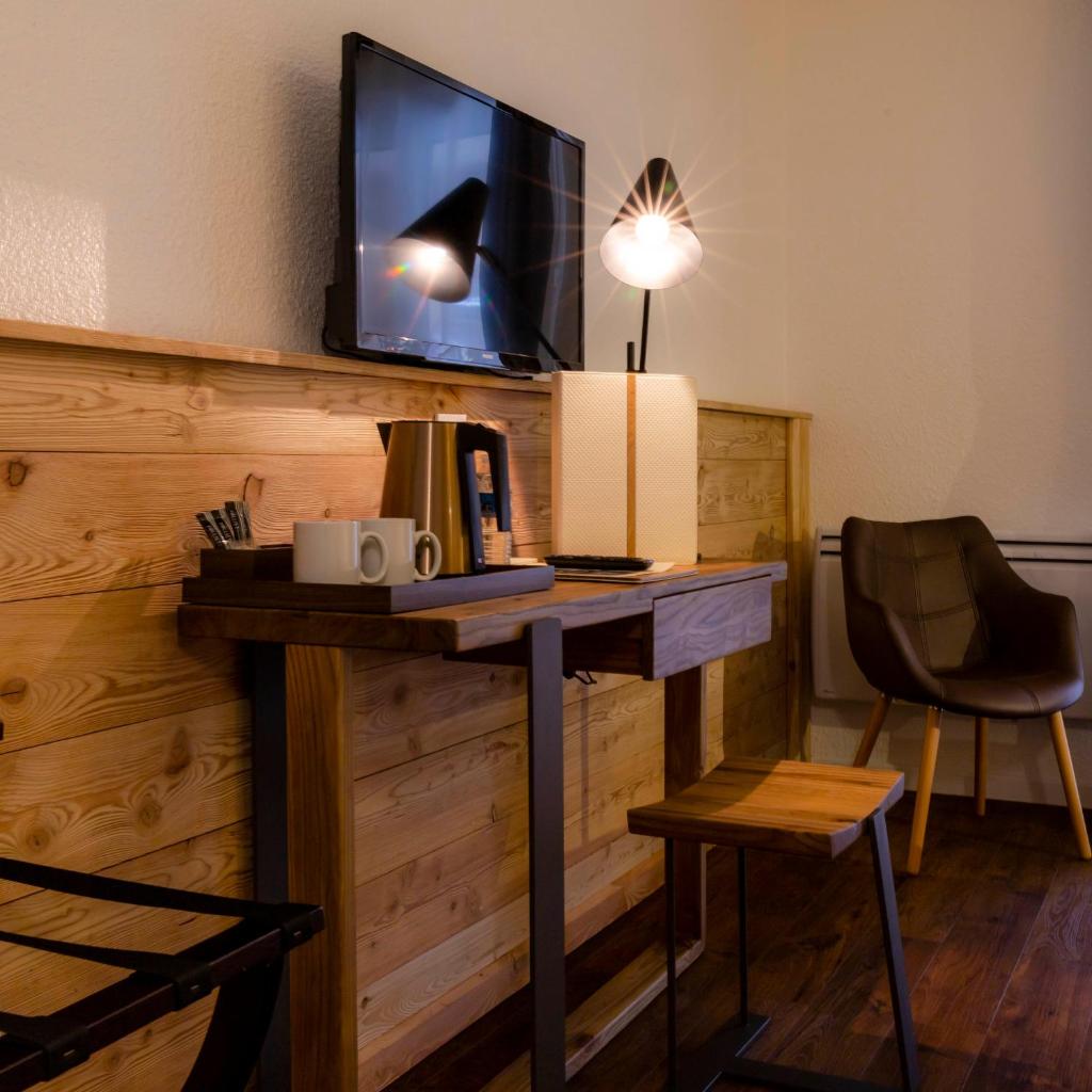 Cette chambre dispose d'un bureau, d'une télévision et d'une chaise. dans l'établissement Hotel SNOW CHILL, à Risoul