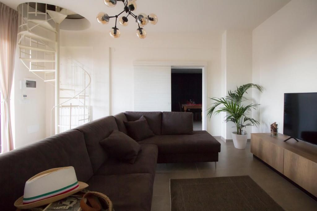 un salon avec un canapé brun et une télévision dans l'établissement Casa di Sara, à Zafferana Etnea