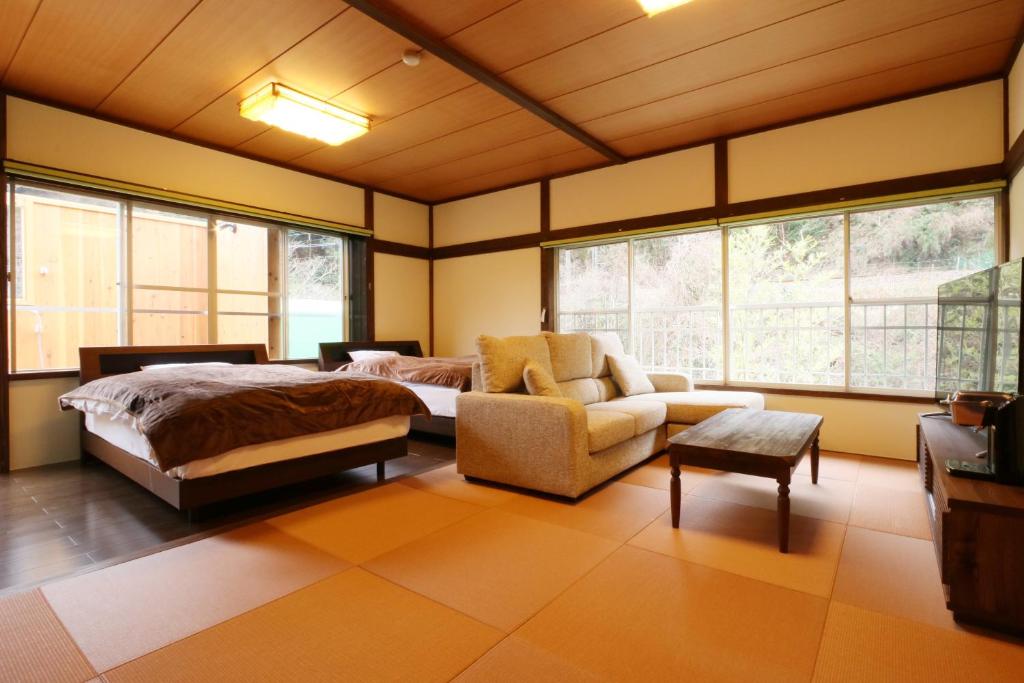 une chambre avec un lit, un canapé et une chaise dans l'établissement Amis Droles アミドローラ LIBERTY RESORT, à Kawazu