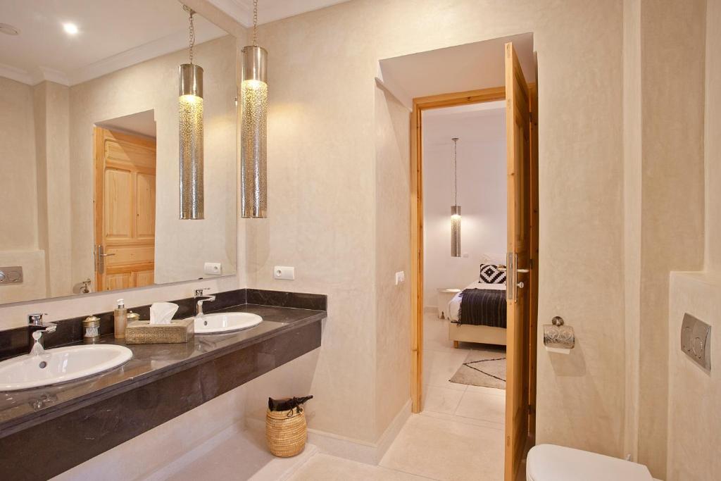 une salle de bain avec deux lavabos et un grand miroir dans l'établissement Riad AL RIAD, à Marrakech
