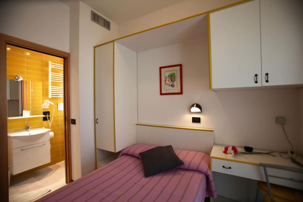 - une petite chambre avec un lit rose et un lavabo dans l'établissement Hotel Biancaneve Wellness, à Marotta