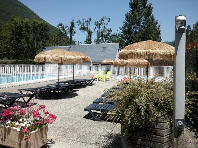un groupe de tables et de parasols à côté d'une piscine dans l'établissement Mobil-home 75 au Camping Le Rioumajou, à Bourisp