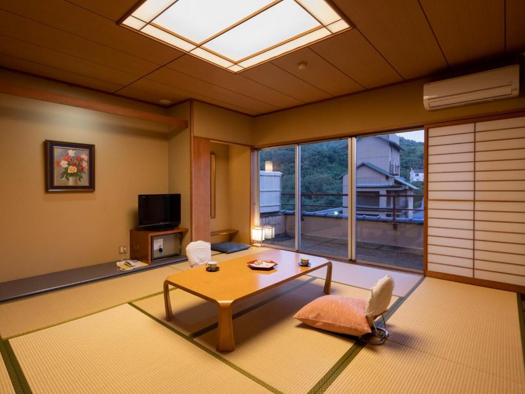 un salon avec une table et une grande fenêtre dans l'établissement Tamai Bekkan, à Matsue